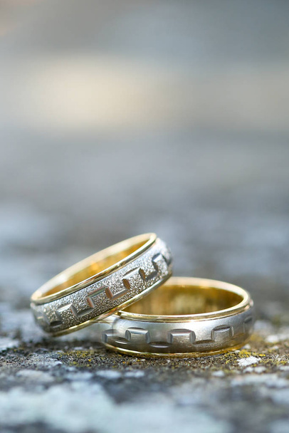Close-up van twee trouwringen op beton met wazige achtergrond - Foto, afbeelding