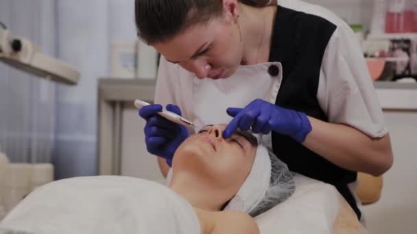 Ammattimainen kosmetologi tekee ultraääni kasvojen puhdistus keski-ikäinen nainen
. - Materiaali, video