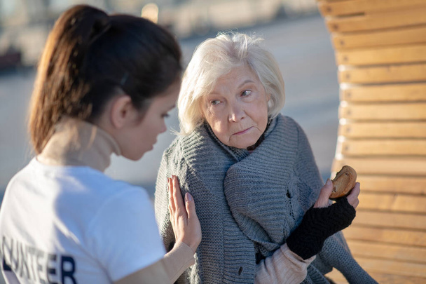 dunkelhaarige freundliche Freiwillige unterstützt ältere Obdachlose - Foto, Bild