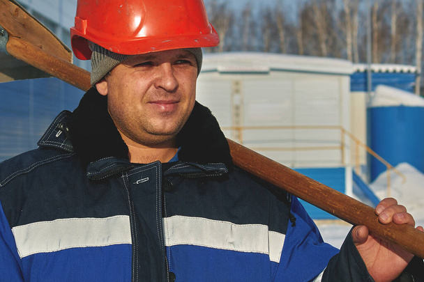 Homme blanc en casque, salopette et avec une pelle. Portrait d'un travailleur en hiver
 - Photo, image