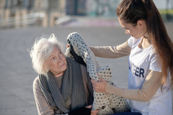 Hasznos önkéntes meleg kabátot hoz a hajléktalan nőnek. - Fotó, kép