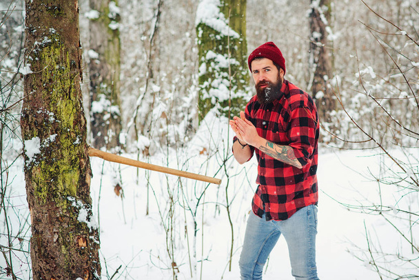 Fejszés férfi a havas téli erdőben. Téli ünnepek. Mentse erdő és tartsa zöld koncepció - Fotó, kép