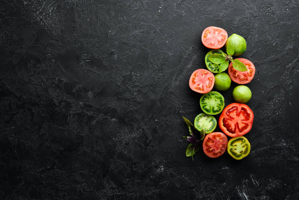 Vegetables. Fresh colored tomatoes On a black stone background. Top view. Free space for your text. - Foto, Bild