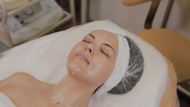 Ammattimainen kosmetologi soveltaa läpinäkyvä kangas kasvot naamio kasvoille
. - Materiaali, video