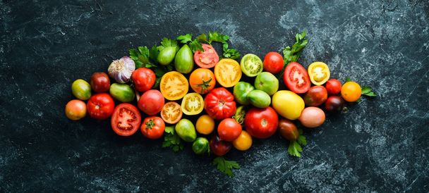 Vegetables. Fresh colored tomatoes On a black stone background. Top view. Free space for your text. - Foto, immagini