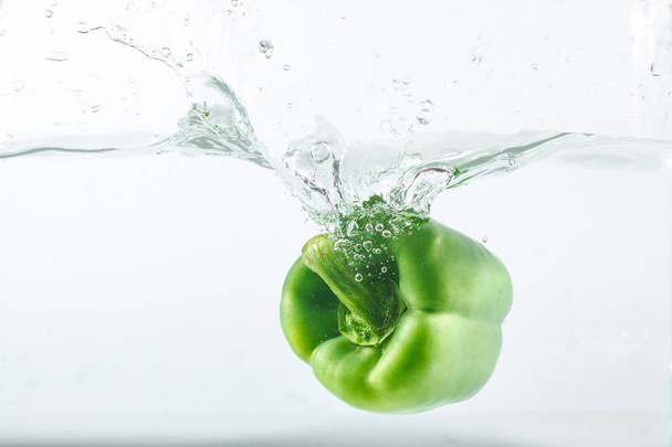 Sweet pepper in water splashes, green sweet pepper on a white background. Sweet peppers are a type of pepper. Not spicy - Фото, зображення