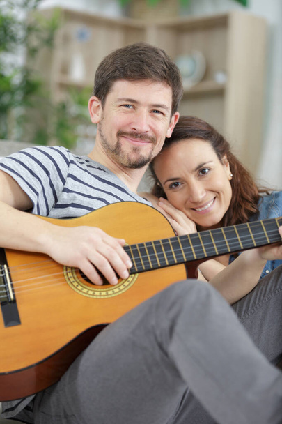 happy young couple resting together on sofa with guitar - Foto, Imagen
