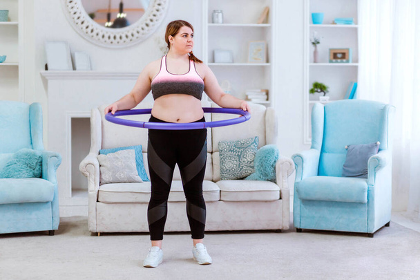 The model is a fat woman, trying to lose weight at home and doing exercises with halajup - Photo, Image