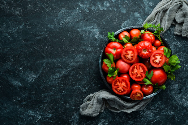 Tomatoes in a plate on a black stone background. Vegetables. Top view. Free space for your text. - Foto, Bild