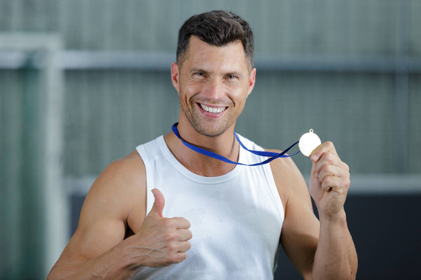 portrait of handsome sportsman showing medal - Zdjęcie, obraz