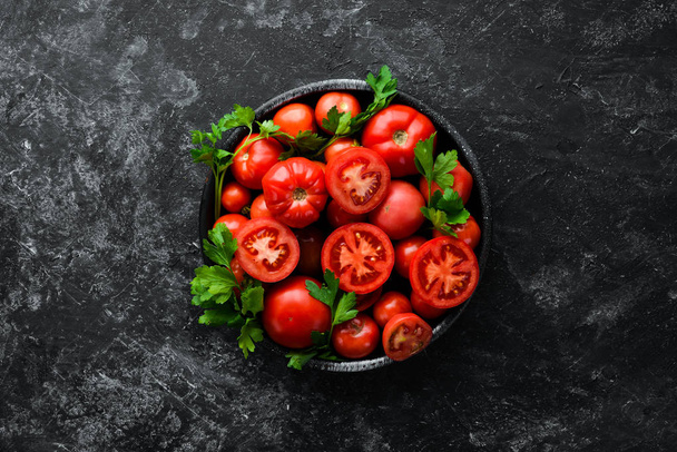 Tomatoes in a plate on a black stone background. Vegetables. Top view. Free space for your text. - Valokuva, kuva