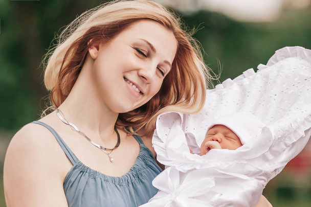 young mom with newborn baby on blurred nature background. - Photo, Image