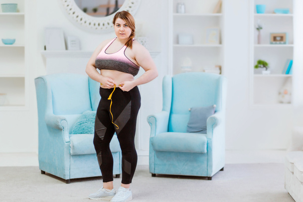 Modelo - mulher gorda, medindo o tamanho da cintura com uma fita métrica
 - Foto, Imagem