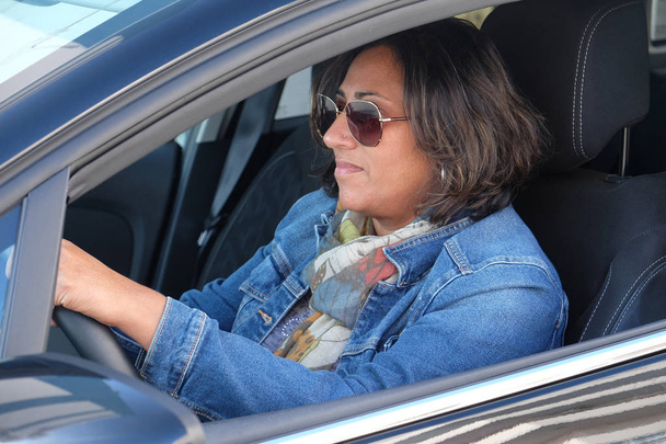 vijfenvijftig jaar oud aziatische vrouw rijden een auto - Foto, afbeelding