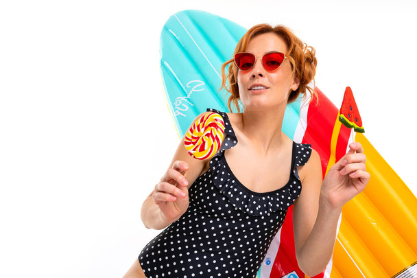 jonge vrouw in zonnebril poseren met snoepjes tegen witte achtergrond   - Foto, afbeelding