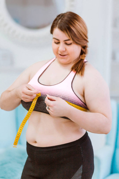 Modelo - mujer gorda, midiendo el tamaño de la cintura con una cinta métrica
 - Foto, imagen