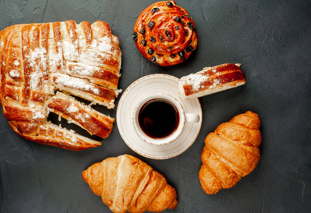 taza y café con producto de panadería sobre un fondo oscuro
 - Foto, Imagen