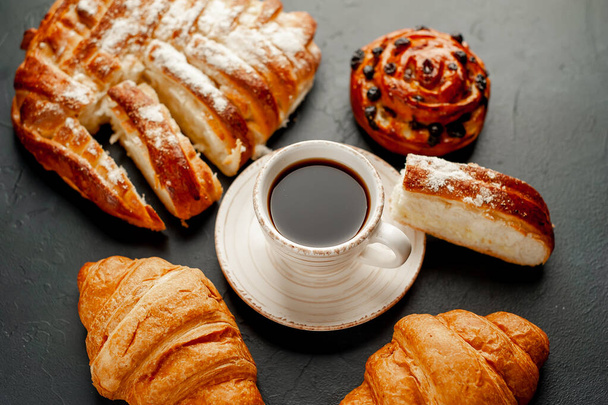 taza y café con producto de panadería sobre un fondo oscuro
 - Foto, Imagen
