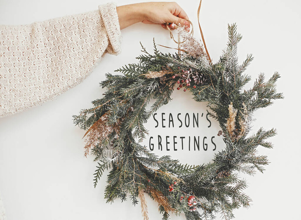 Season's greetings text sign on christmas rustic wreath in girl  - Foto, immagini