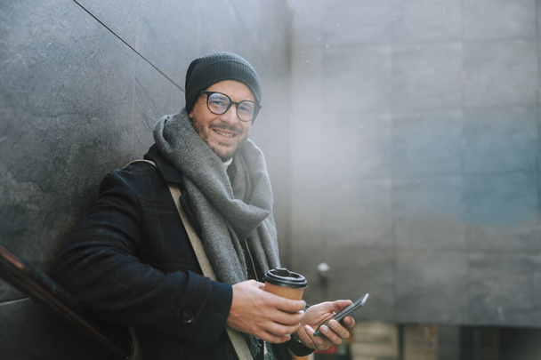 Caucasian smiling man drinking coffee on stairs - Photo, image