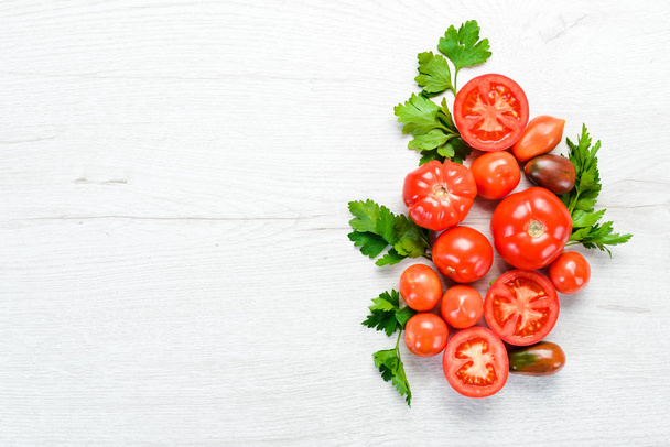 Fresh red tomatoes on white wooden background. Greens. Top view. Free space for your text. - Zdjęcie, obraz