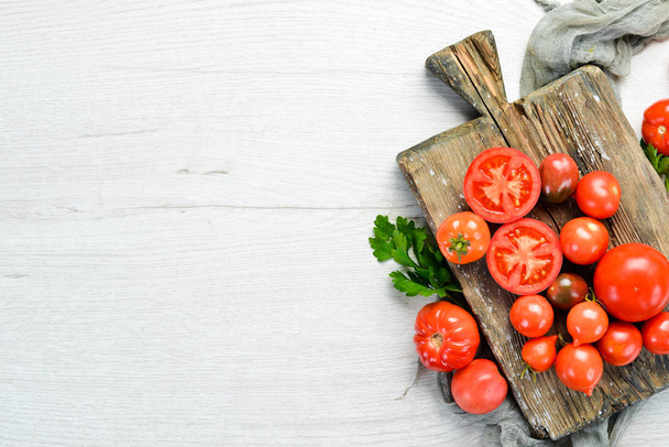 Fresh red tomatoes on white wooden background. Greens. Top view. Free space for your text. - Foto, Bild
