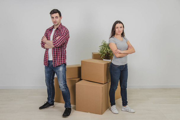 Man and woman standing with hands folded, near stack of carton boxes in their new apartment. - Fotografie, Obrázek