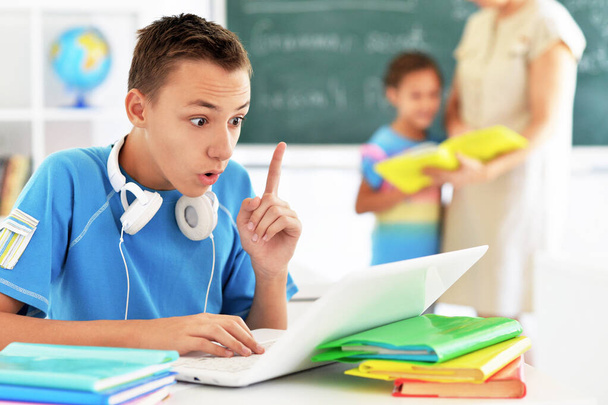 Χαριτωμένο αγόρι που χρησιμοποιεί φορητό υπολογιστή στην αίθουσα τάξη - Φωτογραφία, εικόνα