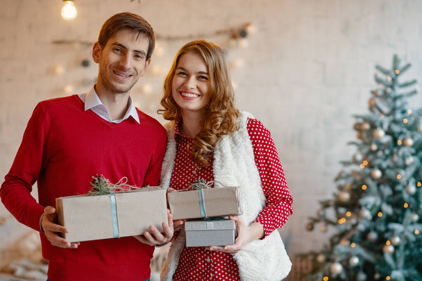 Happy νεαρό ζευγάρι με τα Χριστούγεννα παρουσιάζει - Φωτογραφία, εικόνα