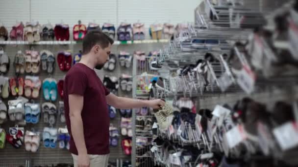 αγοραστής άνθρωπος ψάχνει για ένα μέγεθος των αθλητικών παπουτσιών στο κατάστημα - Πλάνα, βίντεο