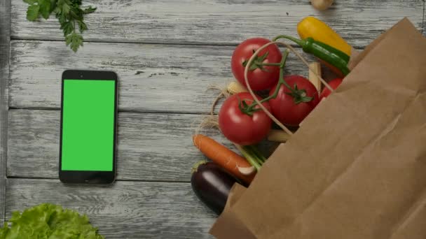 Tomate rodando cerca de verduras y teléfonos inteligentes - Imágenes, Vídeo