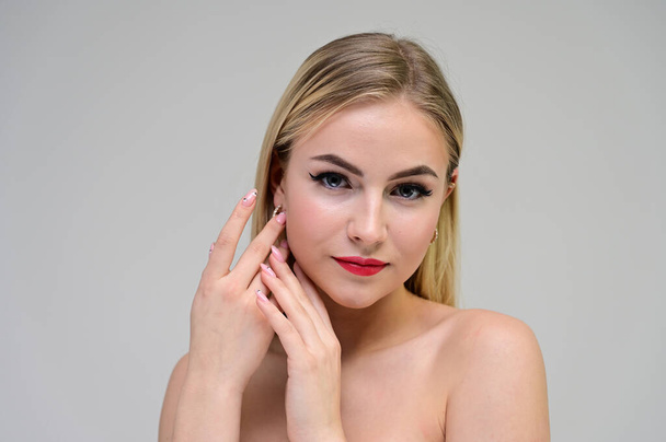 Concept cosmetically, skin rejuvenation. Close-up portrait of a beautiful blonde model on a white background with long hair, excellent makeup, beautiful face and lips. - Fotografie, Obrázek