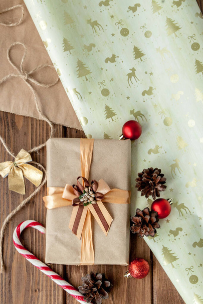 Рождественский фон с рождественскими конусами и игрушками, еловыми ветвями, коробками подарков и украшениями на фоне деревянного стола - Фото, изображение