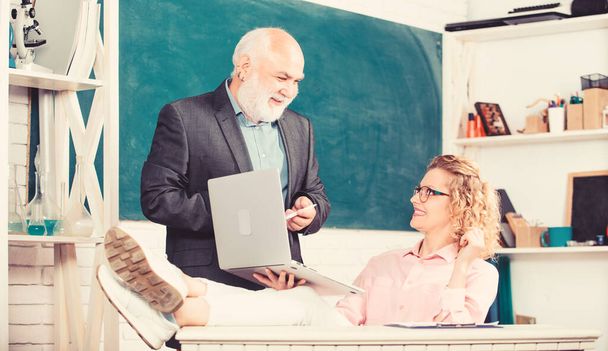 Discussing topic with student or colleague. Man mature school teacher and carefree girl student with laptop. Modern school. High school college university. Communicate clearly and effectively - Foto, imagen