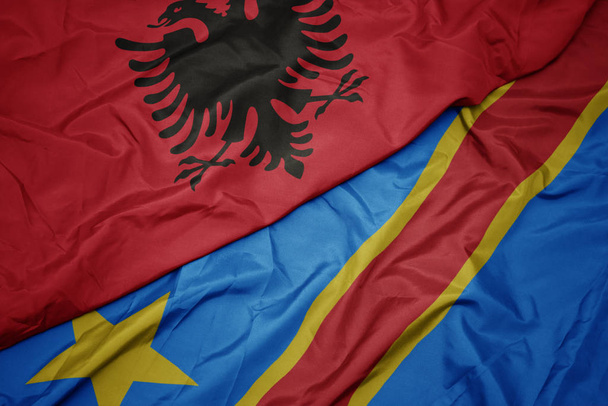 schwenken bunte Flagge der Demokratischen Republik Kongo und Nationalflagge Albaniens. - Foto, Bild