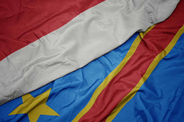 κυματίζει πολύχρωμη σημαία της δημοκρατικής Δημοκρατίας του Κονγκό και εθνική σημαία της Ινδονησίας. - Φωτογραφία, εικόνα