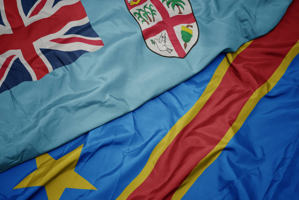 machając barwną flagą demokratycznej republiki Konga i flagi narodowej Fidżi . - Zdjęcie, obraz