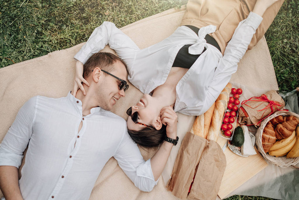 Nuori onnellinen pari pukeutunut kuin valkoinen t-paita hauskaa piknikillä, viikonloppu kaupungin ulkopuolella, loma-ajatus
 - Valokuva, kuva