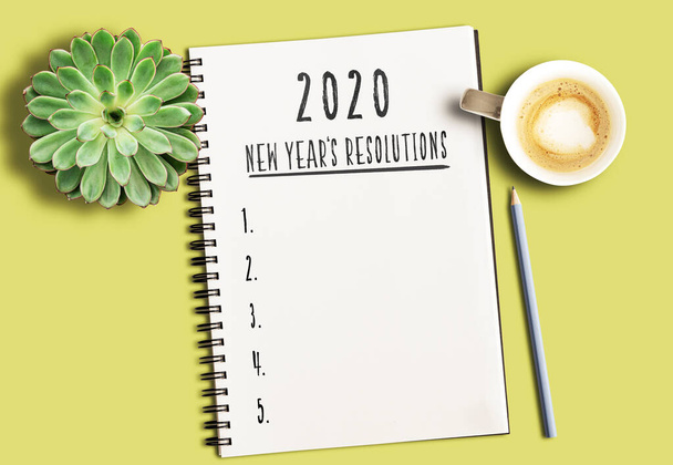 2020 Yeni Yıl Çözümleri metniyle not defteri ve sarı masa üzerinde sulu bitki ve bir fincan kahve ile numaralandırılmış liste. - Fotoğraf, Görsel