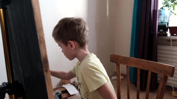 enfant d'âge préscolaire peint sur un chevalet avec de la peinture gouache avec un pinceau. Fusillade par derrière. 4k
 - Séquence, vidéo