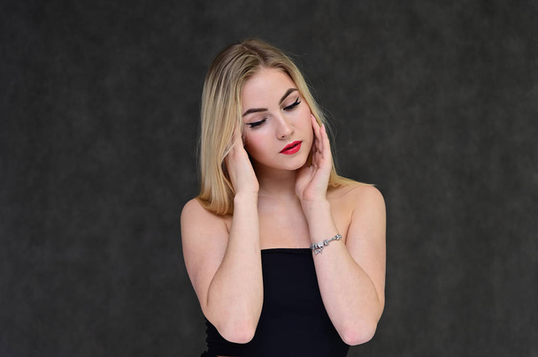The concept of fashionable glamor, cosmetics and beauty with a pretty girl. Portrait of a fashionable beautiful blonde model with long hair, great makeup, on a gray background. - Photo, image