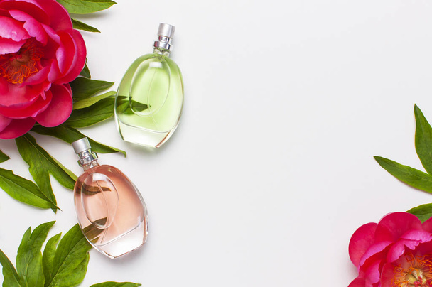 Gyűjtők és rózsaszín virágok pünkösdi rózsa a világosszürke háttér felülnézet lakás feküdt másolási hely. Illatszerek, kozmetikumok, női kiegészítők, illatanyag-gyűjtemény. Finom parfümös üveg - Fotó, kép