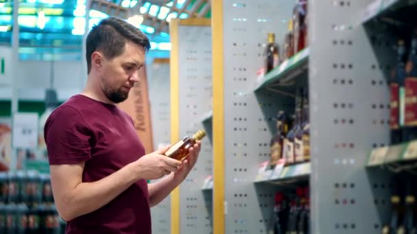 άνθρωπος επιλέγει κονιάκ στο εμπορικό κέντρο στο σούπερ μάρκετ - Πλάνα, βίντεο