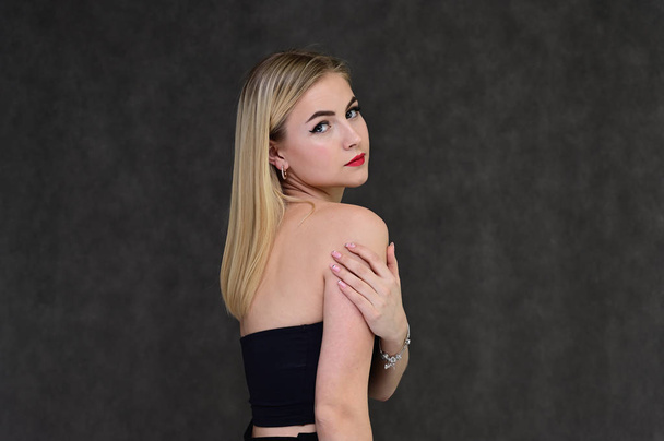 The concept of fashionable glamor, cosmetics and beauty with a pretty girl. Portrait of a fashionable beautiful blonde model with long hair, great makeup, on a gray background. - Fotografie, Obrázek