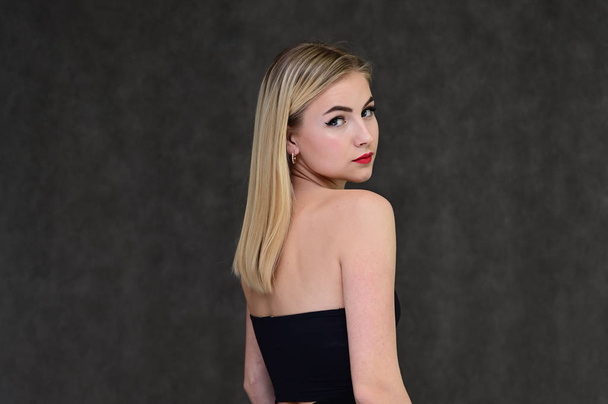 The concept of fashionable glamor, cosmetics and beauty with a pretty girl. Portrait of a fashionable beautiful blonde model with long hair, great makeup, on a gray background. - Foto, Bild