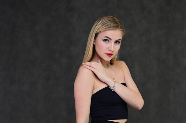 The concept of fashionable glamor, cosmetics and beauty with a pretty girl. Portrait of a fashionable beautiful blonde model with long hair, great makeup, on a gray background. - Foto, immagini