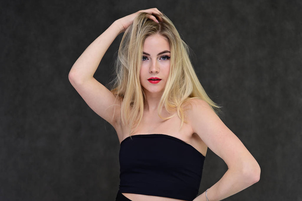 The concept of fashionable glamor, cosmetics and beauty with a pretty girl. Portrait of a fashionable beautiful blonde model with long hair, great makeup, on a gray background. - Φωτογραφία, εικόνα