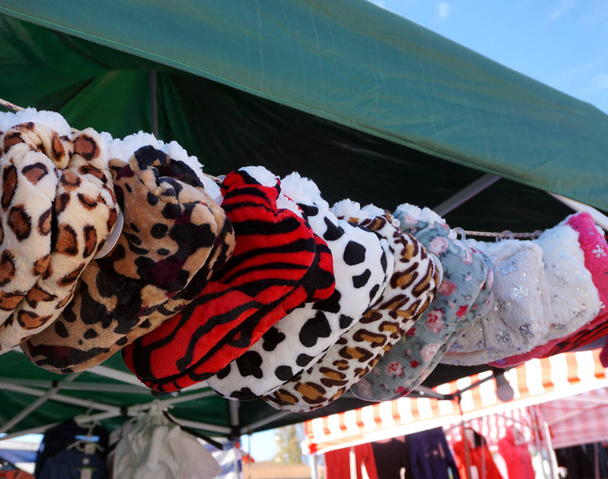 Chinelos quentes de inverno feitos de pele sintética falsa, alinhados na corda e se preparando para vender no festival de rua popular
 - Foto, Imagem