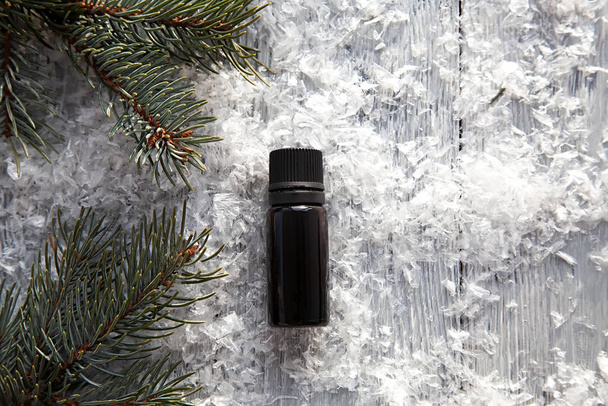 borovice aroma olej extrakt přírodní v kosmetické láhvi aromaterapie na zimním zasněženém pozadí - Fotografie, Obrázek