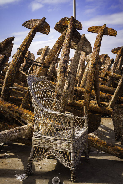 Rusty Anchors And Abandoned Wicker Chair In Fishing Port - Fotografie, Obrázek